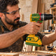 Carpenter driving a screw into a wooden shelf with a compact cordless brushless drill
